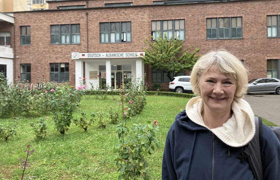 Farbfoto von Edda Bruch vor der Deutsch-Albanischen Schule in Tirana im Oktober 2025.